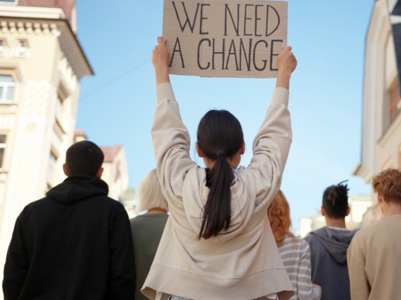 Youth holding signs in the street saying "we need a change"