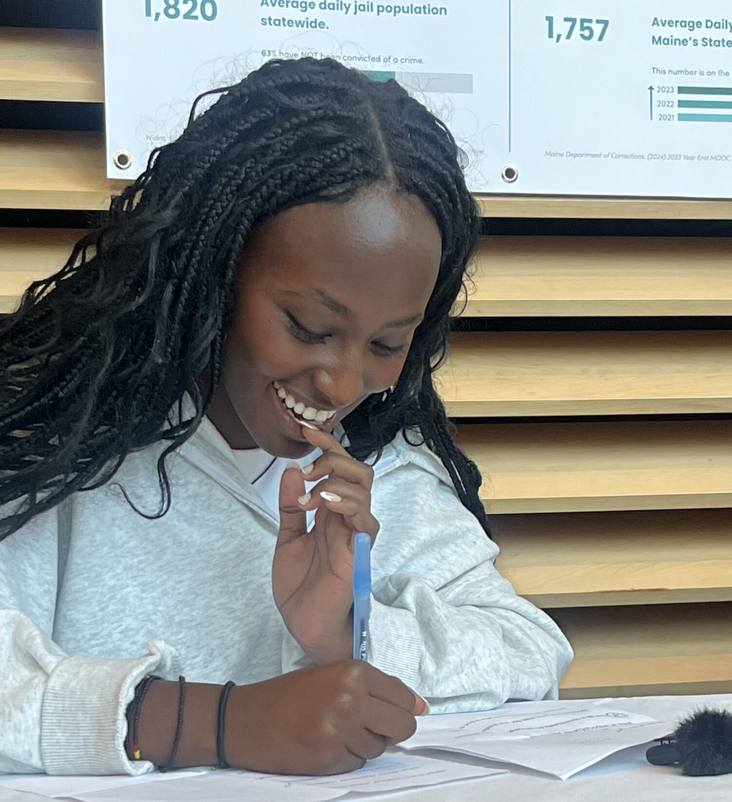 A young person smiling as they write