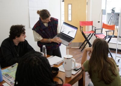 A group of young people look at a laptop together